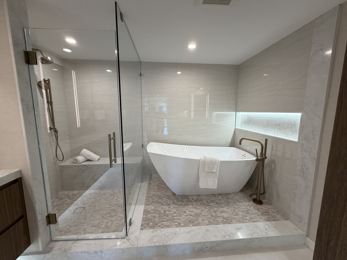 Modern bathroom with glass walk-in shower, freestanding white tub, tiled walls, and patterned floor.